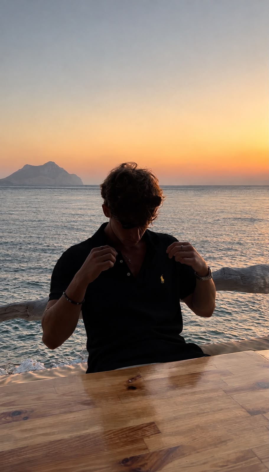 Homem vestindo polo preta Ralph Lauren à beira-mar